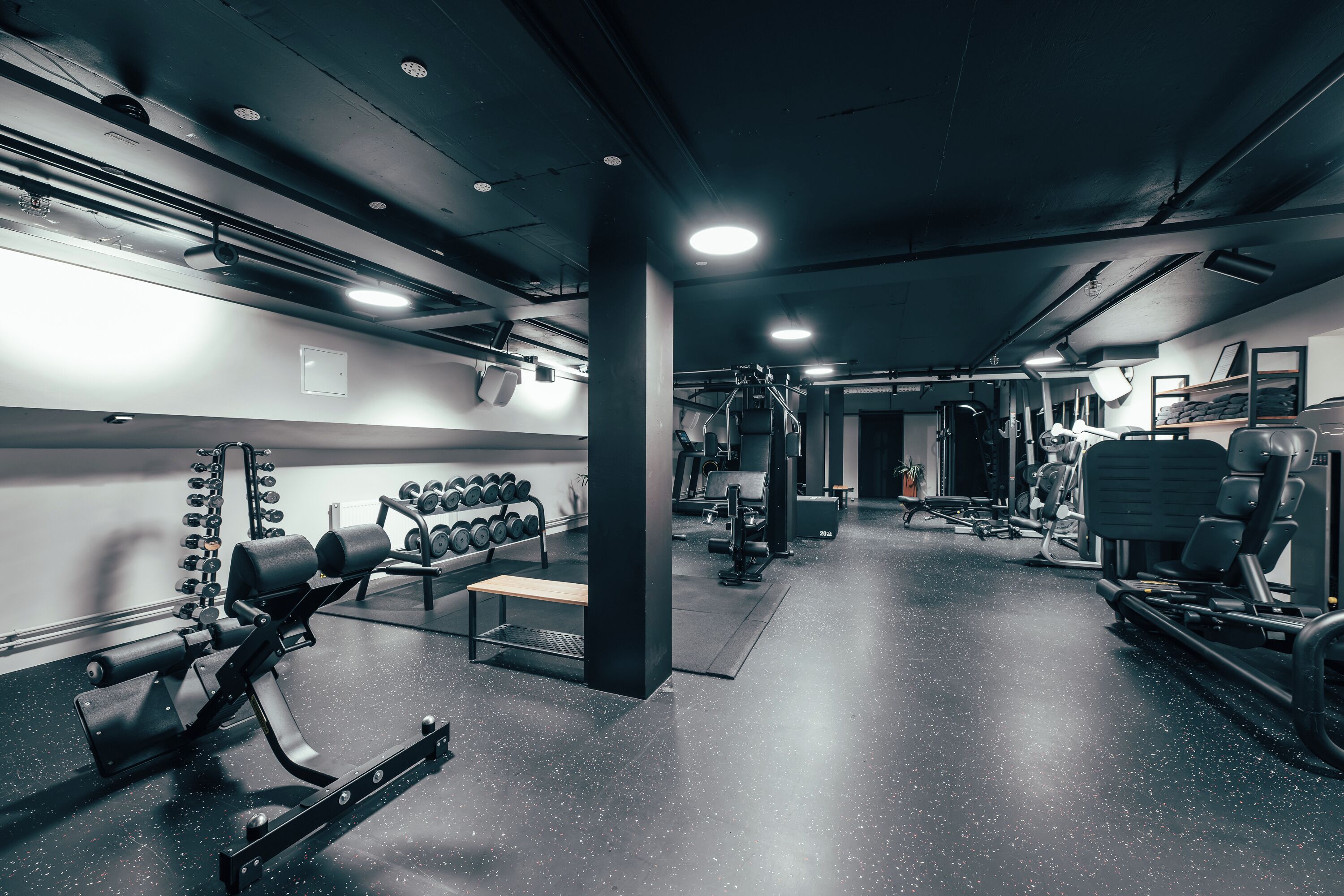 A gym with various exercise equipment, including dumbbells, benches, and weight machines.