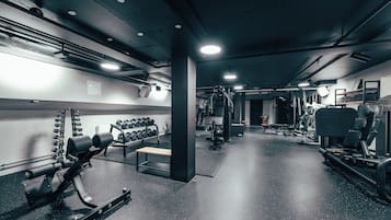 A gym with various exercise equipment, including dumbbells, benches, and weight machines.