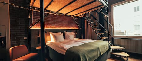 A modern bedroom with a loft bed, a staircase, and a view of the city.