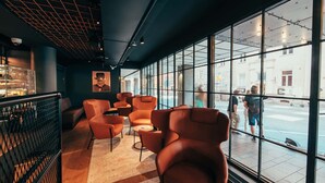 A modern interior with leather chairs, a coffee bar, and large windows offering a view of the street. - Clarion Hotel Mestari (Helsinki)