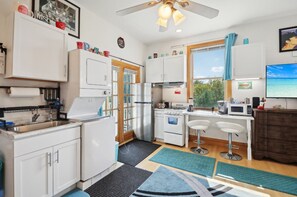 A compact kitchen with white cabinets, a stove, a sink, and a microwave. There are two bar stools and a window with a view of the outdoors. - Starlight Tower Suite 1 Bedroom With Stunning Views 1 Villa by RedAwning (Fort Atkinson)