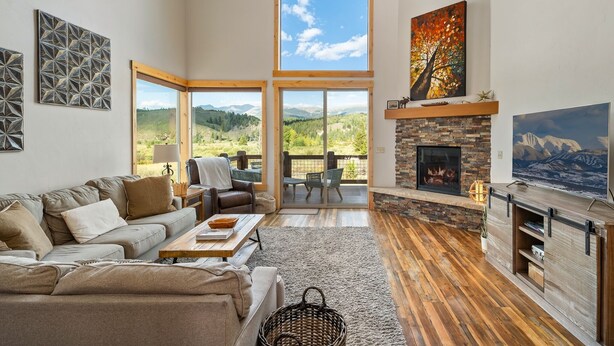 A spacious living room with a large window, a fireplace, and a cozy seating area. - Mountain Willow At Grand Park 4 Bedroom Home by RedAwning (Fraser)