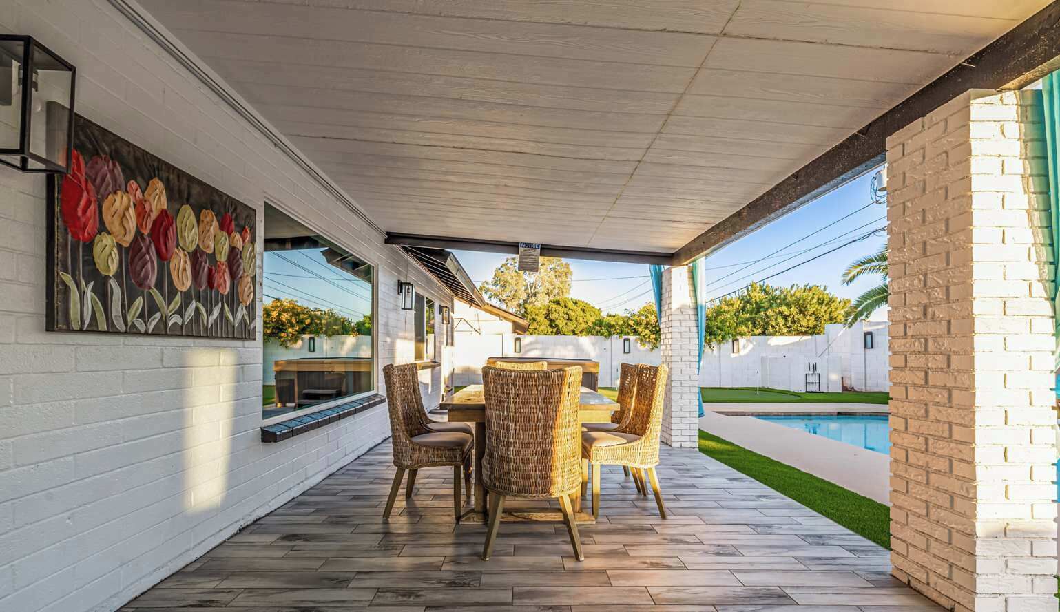 An outdoor patio with a pool, wicker furniture, and a mural on the wall.