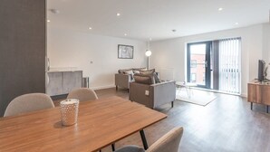 Ein modernes Wohnzimmer mit Essbereich, einer Sofagarnitur und einem großen Fenster mit Blick.