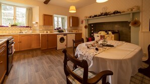 Una cocina acogedora con armarios de madera, lavadora y comedor con una mesa lista para dos.
