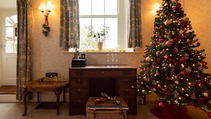 Una habitación acogedora con un escritorio de madera, una cesta de mimbre y un árbol de Navidad.