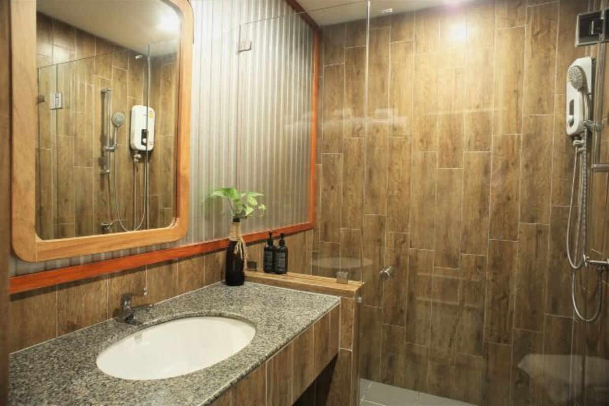 A modern bathroom with a granite sink, a large mirror, and a shower area.