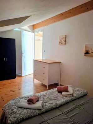 A bedroom with a bed, a dresser, and a door leading to a bathroom.