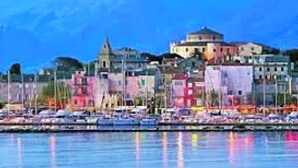 A coastal town with a prominent church on a hill, colorful buildings, and boats docked along the waterfront. - 3 bedroom apartment with swimming pool 3km from St Florent  (Oletta)