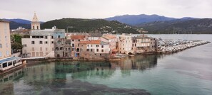 Eine Küstenstadt mit historischen Gebäuden, einem Yachthafen und Bergen im Hintergrund.