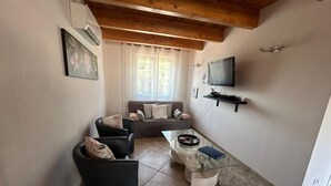 A living room with a sofa, a glass coffee table, and a TV mounted on the wall. - 3 bedroom apartment with swimming pool 3km from St Florent  (Oletta)