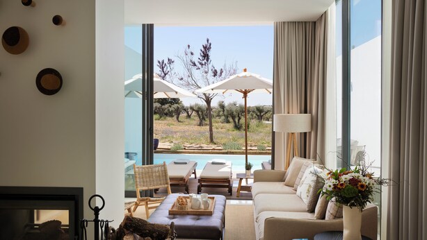 Una sala de estar moderna con vista a una piscina, una chimenea y un comedor con mobiliario exterior.