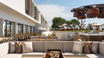 A modern outdoor seating area with a sofa, tables, and umbrellas.