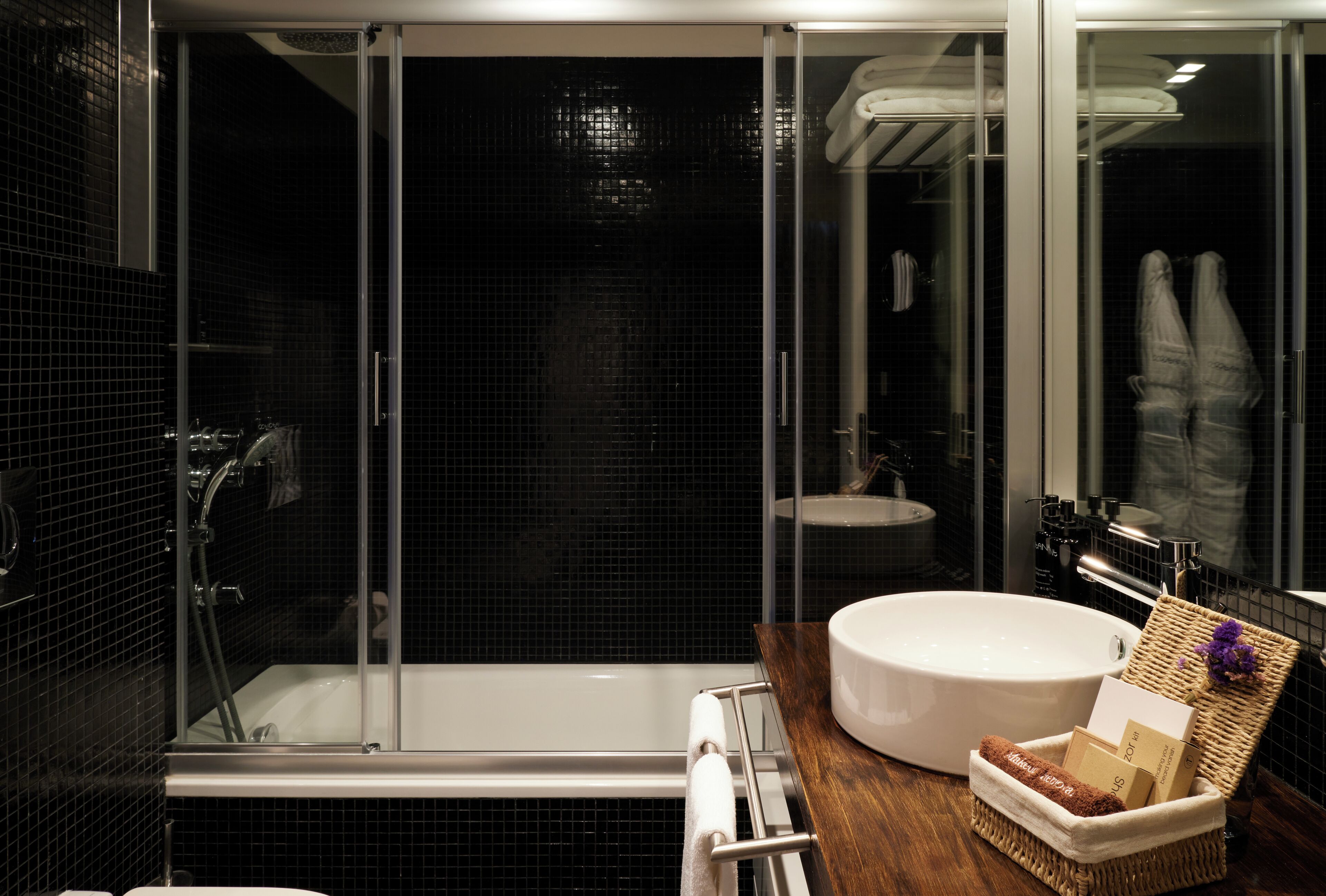 Une salle de bain moderne avec une douche à parois de verre, un lavabo rond et un meuble-lavabo en bois.