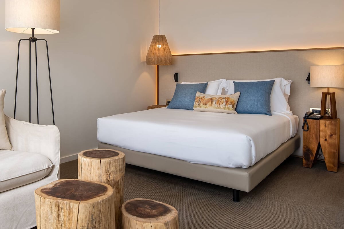 Ein Hotelzimmer mit einem Bett, einer Couch, einer Stehlampe, einem Nachttisch und einer Wandlampe.
