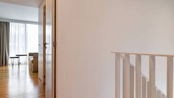 Une chambre d’hôtel moderne avec un plancher en bois, un mur blanc et un escalier doté de rampes blanches.