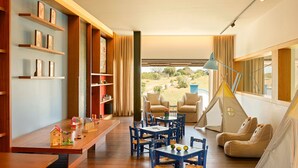 Una habitación acogedora con estanterías de madera, una mesa de comedor, sillas azules, un sofá y una tienda tipi.