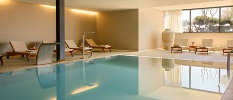 A swimming pool with lounge chairs and a large vase.