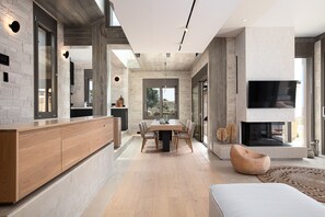Una cocina moderna con encimera de madera, una zona de comedor con mesa y sillas, y una chimenea.