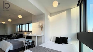 A modern hotel room with two beds, a desk, and a large window. - b hotel Neko Yard | Modern City-Center Studio (Naka Ward, Hiroshima)