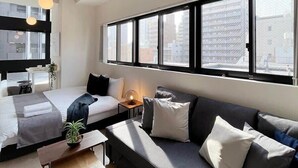 Ein modernes Hotelzimmer mit einem großen Bett, einer Couch, einem kleinen Tisch und einem Deckenventilator.