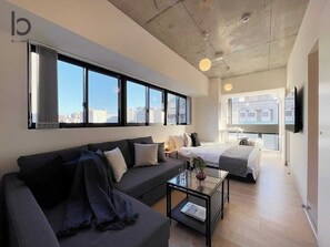 Een moderne hotelkamer met een bank, een bed, een tafeltje en een televisie.