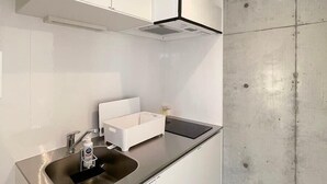 Una cocina moderna con armarios blancos, un lavamanos de acero inoxidable y una pared de concreto decorativa.