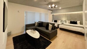 Moderni hotellihuone, jossa on sohva, sänky, televisio ja kattovalaisin.