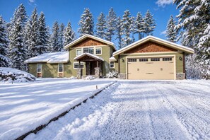 Une maison à deux étages avec un garage et une allée recouverte de neige.