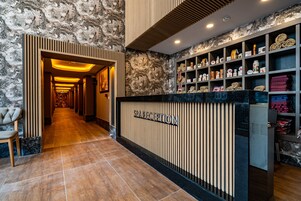 A reception area with a marble wall, a reception desk, and shelves with various items.