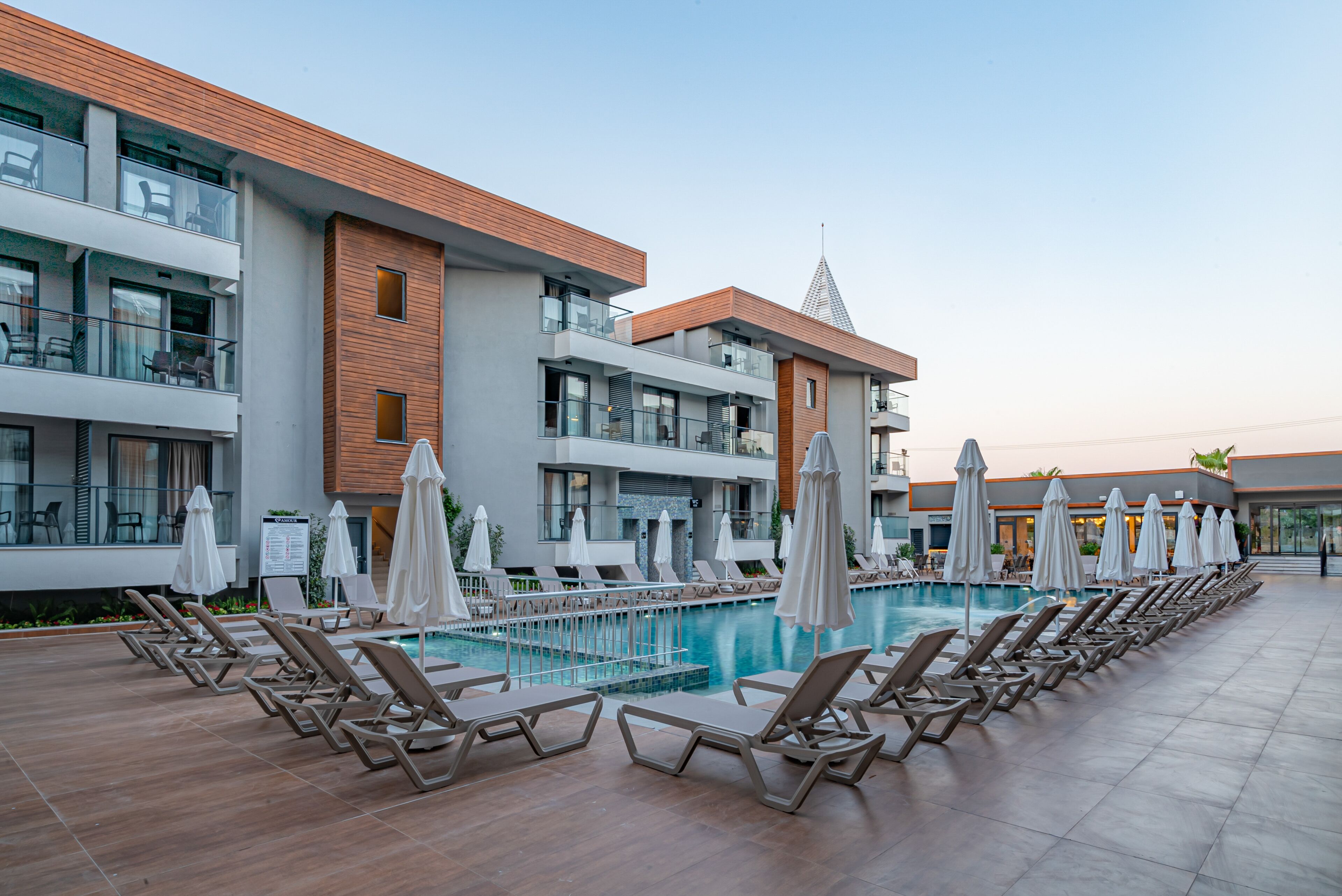Un hotel moderno con piscina, tumbonas y sombrillas.
