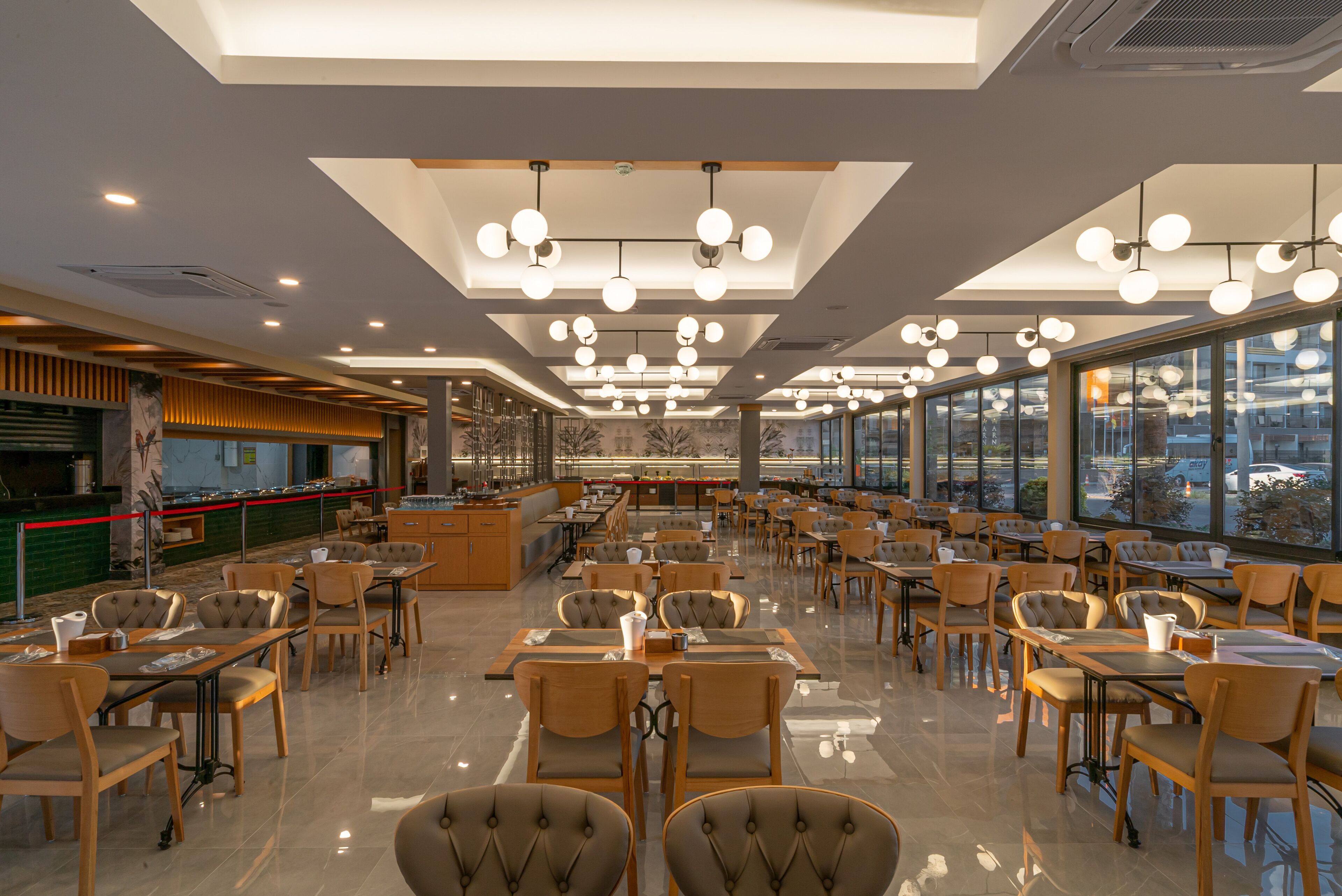 Un restaurante amplio con decoración moderna, ventanas grandes y diversas opciones de asientos.