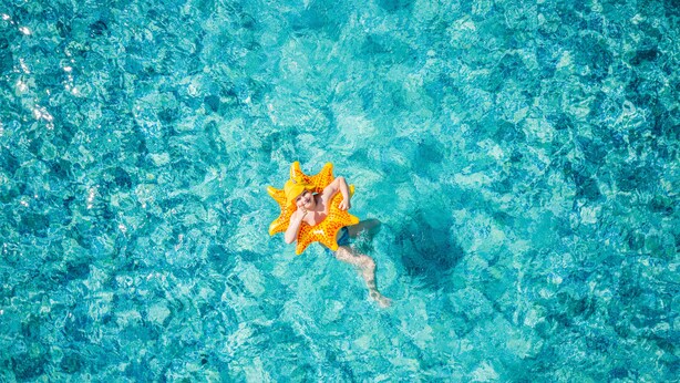 Una persona flota en una piscina con un flotador con forma de estrella de mar.