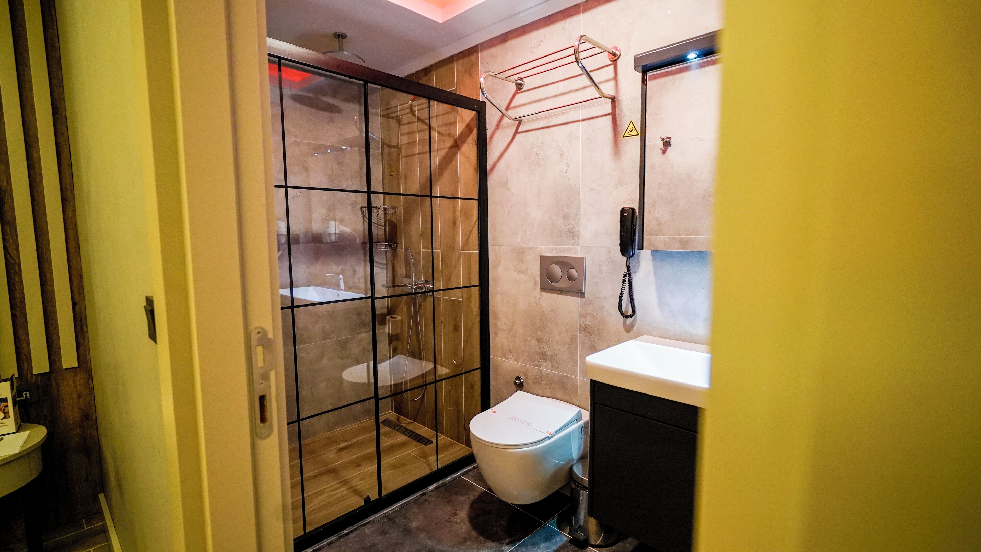 Een moderne badkamer met een glazen douchecabine, toilet en wastafel.