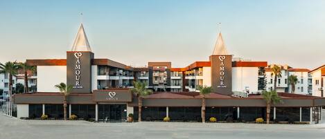 Un hotel con dos torres destacadas, una fachada moderna y un acceso ajardinado.