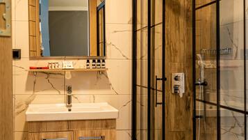 A modern bathroom with a marble vanity, a glass-enclosed shower, and wooden cabinetry.