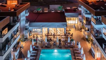 A hotel with a central swimming pool, multiple balconies, and outdoor seating areas.