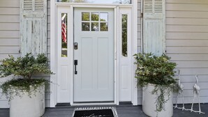 A white front door with a glass panel, flanked by two potted plants, and a welcome mat at the entrance. - 3 bedroom, short walk to the beach with an amazing game room! (Hilton Head Island)