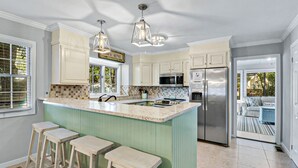 A modern kitchen with a large island, stainless steel appliances, and a view to the outdoor seating area. - 3 bedroom, short walk to the beach with an amazing game room! (Hilton Head Island)