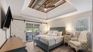 A bedroom with a bed, a chair, a dresser, a TV, and a sliding door to a balcony. - 3 bedroom, short walk to the beach with an amazing game room! (Hilton Head Island)