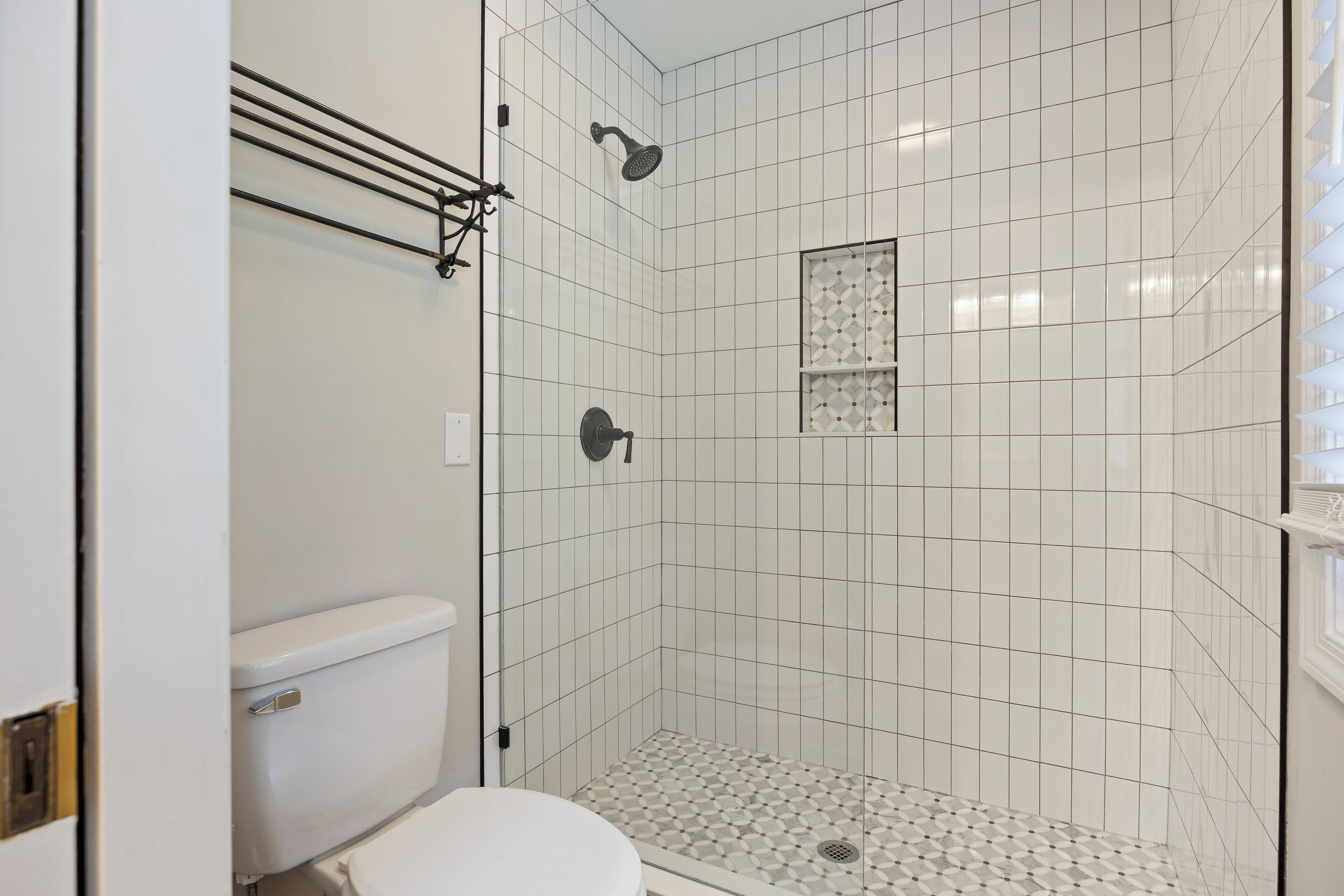Ein Badezimmer mit Dusche, Toilette und Fliesenboden.