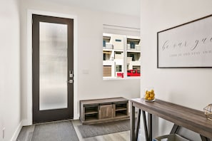 Enter a welcoming space with a dark-colored door, bench, and glass table, perfect for placing personal items.