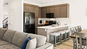Una cocina moderna con armarios de madera, una isla central y taburetes de bar.