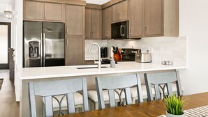 Una cocina moderna con armarios de madera, electrodomésticos de acero inoxidable y encimera blanca.