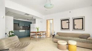 Una sala de estar moderna con un sofá, una mesa de comedor con sillas y una cocina al fondo.