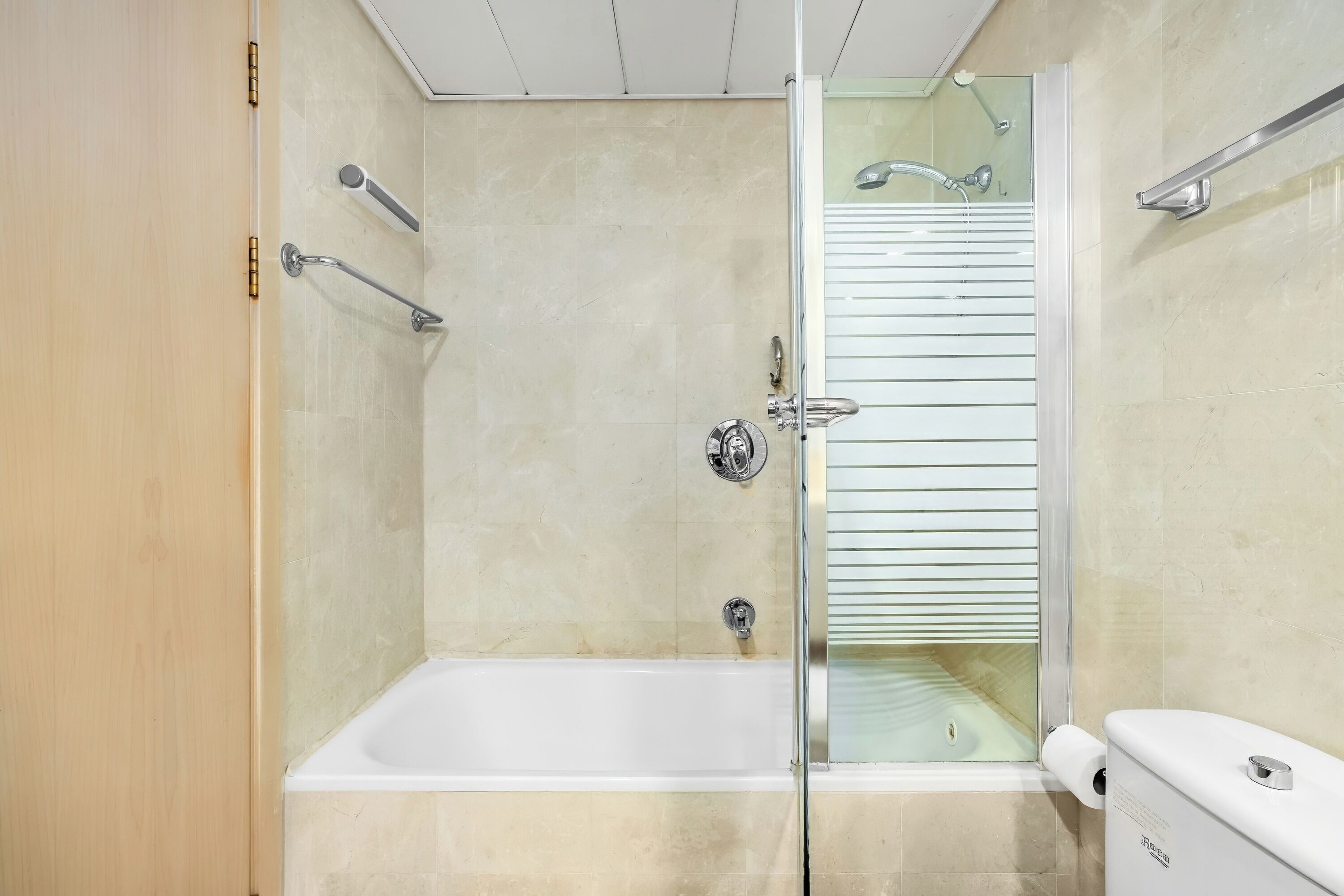 A modern bathroom with a glass-enclosed shower, a white bathtub, and a toilet.