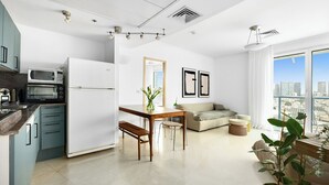 Un apartamento moderno con cocina, comedor y sala de estar. Cuenta con un ventanal con vistas a la ciudad, una mesa de comedor con sillas y un sofá.