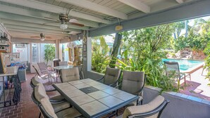 A covered outdoor dining area with a pool view, furnished with chairs and tables, and an office sign. - Richard's Motel (Hollywood)