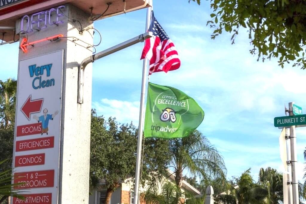 A sign with 'Very Clean' and arrows pointing to different room types, an American flag, and a 'Certified Excellence' flag.