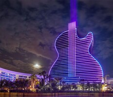 A large building with a guitar-shaped design, illuminated with purple and blue lights.